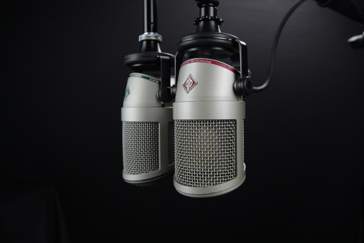 Zwei Mikrofone hängen vor einem schwarzen Hintergrund.